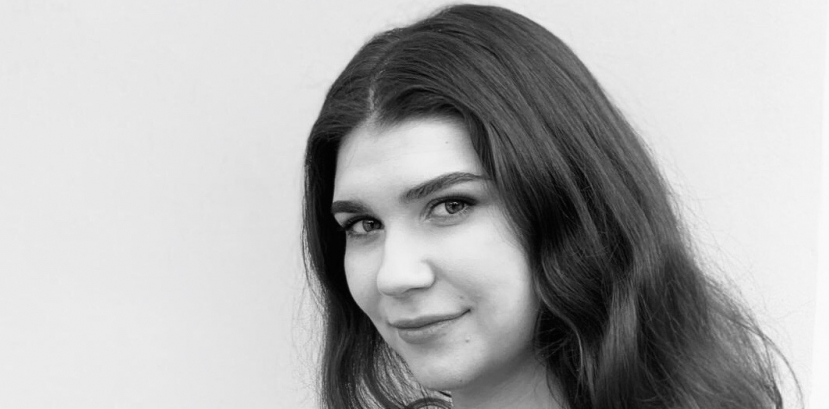 młoda kobieta ustawiona bokiem, długie kręcone włosy swobodnie opadają na ramiona