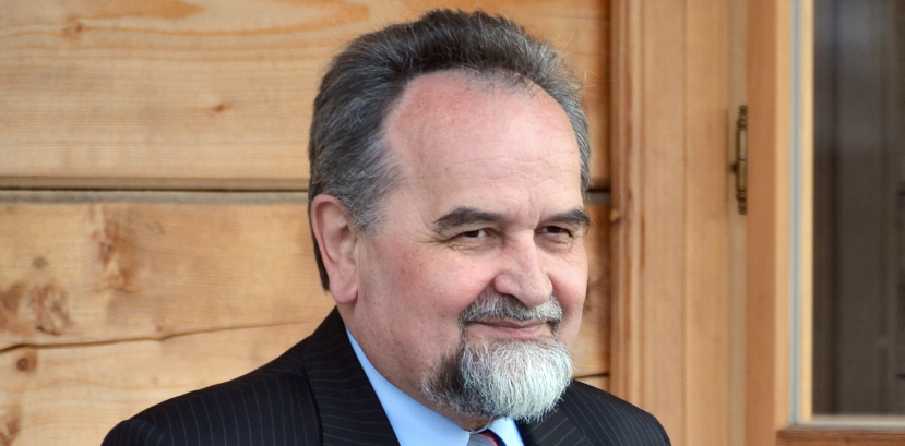 popiersie uśmiechajacego się mężczyzny w garniturze i krawacie