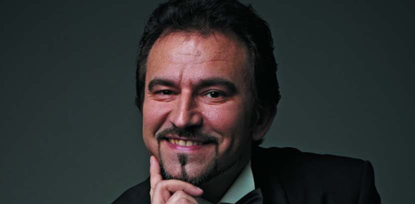 mężczyzna w eleganckim stroju, prawdopodonie fraku, koszuli i z muszka pod szyją, podpiera głowę, uśmiecha się